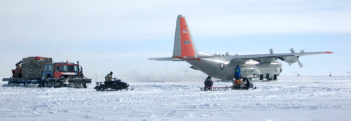 Cargo has just been rolled onto the new off-load sled and is being dragged away while the plane prepares for departure.