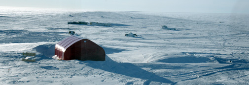 The garage surrounded by snow drifts.